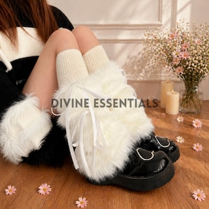 May include: Black patent leather platform shoes with white faux fur leg warmers and cream-coloured socks. The shoes have silver buckles and a heart-shaped design. The text "DIVINE ESSENTIALS" is visible on the leg warmers.