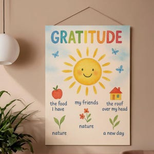 May include: A watercolor-style wall art print with the word "GRATITUDE" in colorful letters. The artwork features a smiling sun, butterflies, an apple, flowers, a house, and text that reads "the food I have", "my friends", "the roof over my head", "nature", and "a new day".