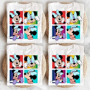 May include: Four white t-shirts with a colorful graphic of Minnie Mouse. Each shirt features a grid of four images of Minnie Mouse with a light blue bow. The background colors are red, yellow, green, and blue.