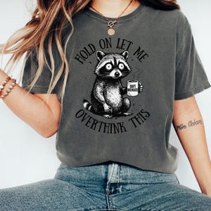 Raccoon shirt in Pepper — Hold On Let Me Overthink This graphic tee on model — Comfort Colors 1717 dark colorway — oversized funny shirt for women — raccoon meme tee — soft menace apparel