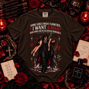 Espresso brown Comfort Colors 1717 dark romance reader tee featuring distressed cream and blood red artwork of a brooding fictional book boyfriend carrying a woman with “Some Girls Want Flowers, I Want a Man Who Looks Like He Escaped My Bookshelf.” Gothic bookish shirt for spicy book lovers, morally gray men fans, fictional boyfriend readers, BookTok romance readers, dark academia style, and romance novel lovers. Soft Menace Co. graphic tee.
