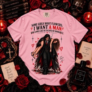 Blossom pink Comfort Colors 1717 dark romance shirt featuring black and deep red distressed artwork with a fictional book boyfriend carrying a woman and “Some Girls Want Flowers, I Want a Man Who Looks Like He Escaped My Bookshelf.” Feminine gothic bookish tee for spicy romance readers, BookTok girls, fictional men lovers, morally gray character fans, romance book readers, and women who love dark romance aesthetic clothing. Soft Menace Co.