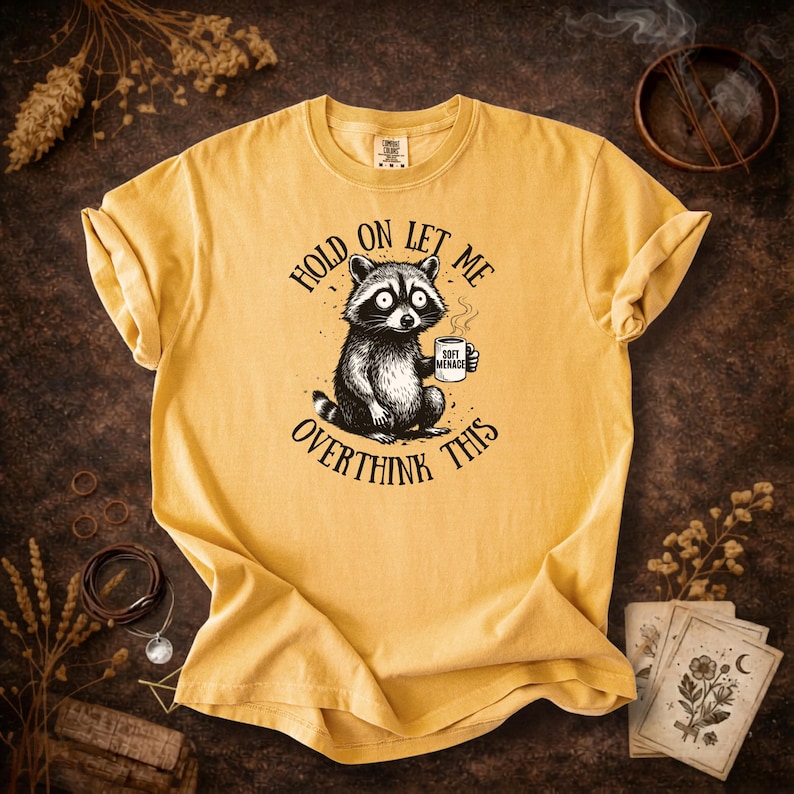 Hold On Let Me Overthink This shirt in Mustard — Comfort Colors 1717 raccoon graphic tee — warm yellow colorway flat lay — funny women’s tshirt — panic raccoon meme shirt — soft garment dyed cotton