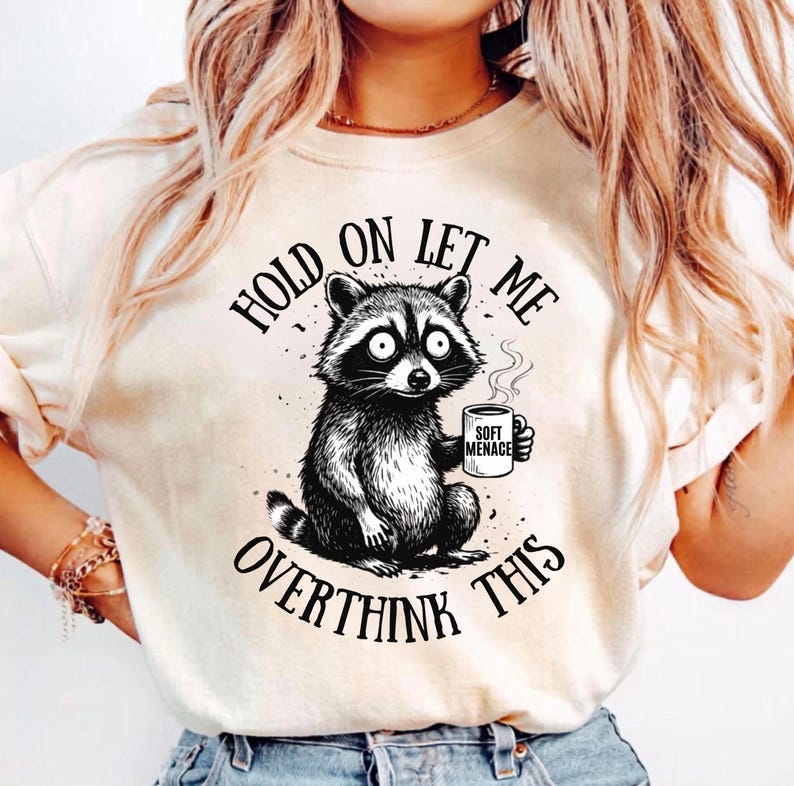 Raccoon shirt in Ivory — Hold On Let Me Overthink This graphic tee with panic-eyed raccoon holding Soft Menace mug — Comfort Colors 1717 — soft oversized fit — funny raccoon shirt for women