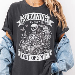 Pepper skeleton shirt worn with denim jacket. Gothic coffin and roses graphic tee on Comfort Colors 1717. Dark humor dark academia shirt — Surviving Purely Out Of Spite. Soft garment-dyed blank.​​​​​​​​​​​​​​​​