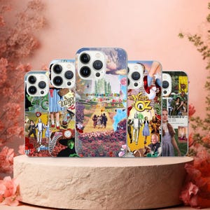 May include: Five phone cases with designs inspired by "The Wizard of Oz." Each case displays a different collage of scenes and characters from the film, with bright colours and text. The cases are presented on a round, light-coloured plinth.
