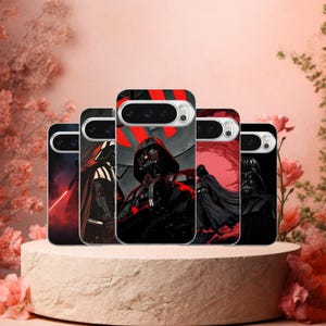 May include: A collection of phone cases featuring Darth Vader from Star Wars. The cases display various artistic renderings of the character in black, red, and gray tones. The cases are displayed on a light brown pedestal with a floral background.