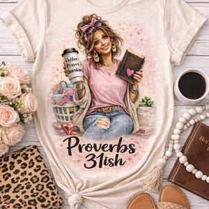 Peut inclure: T-shirt beige avec un motif d'une femme tenant une tasse de café et un livre, avec le texte "Coffee, Prayer, Chocolate" et "Proverbs 31ish". Le motif comprend un panier de vêtements et un cœur rose.