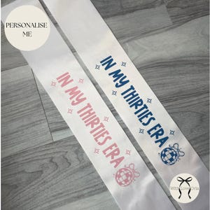 May include: Two white satin sashes featuring the text IN MY THIRTIES ERA in pink and dark blue respectively. Each sash includes small star icons and a disco ball graphic. The sashes are displayed side by side, showcasing the printed designs.