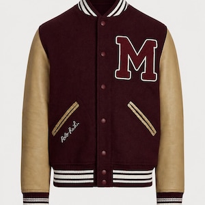 May include: A varsity jacket with a dark burgundy wool-blend body and tan leather sleeves. It features a white-trimmed letter M on the chest, striped ribbed collar and cuffs, snap button closures, and the script text Polo R.L. on the pocket.