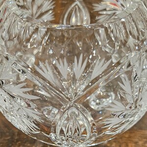 May include: A clear, cut-glass bowl with intricate floral and geometric patterns. The bowl's design features detailed etched lines and shapes, creating a sparkling effect. The bowl is likely used for decorative purposes or serving.