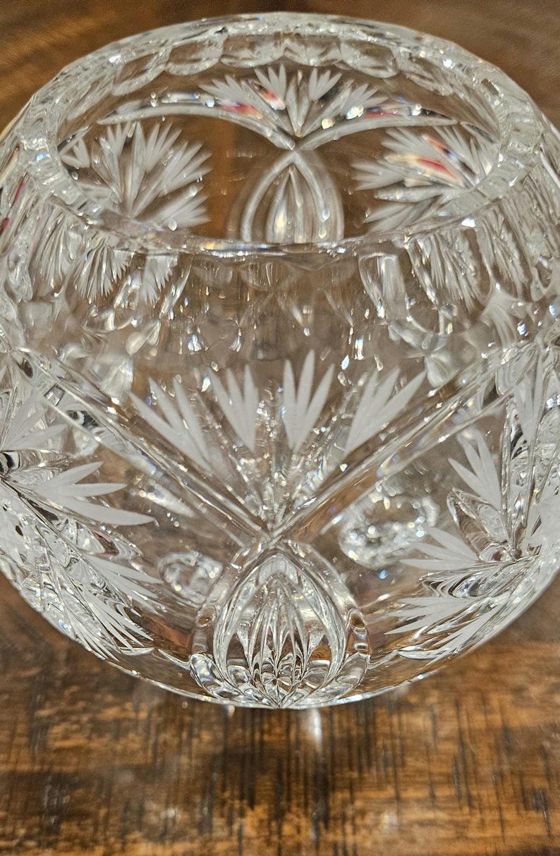 May include: A clear, cut-glass bowl with intricate floral and geometric patterns. The bowl's design features detailed etched lines and shapes, creating a sparkling effect. The bowl is likely used for decorative purposes or serving.