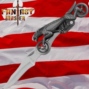 May include: A silver-toned folding knife featuring a handle shaped like a mechanical panther with wheels. The blade is pointed and metallic. The text FANTASY MASTER is visible in the upper left corner against a red, white, and blue flag background.