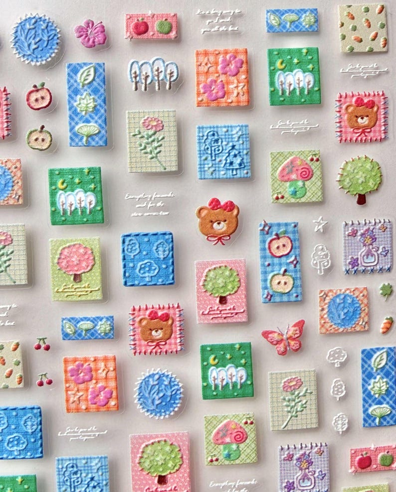 May include: A collection of colorful, textured stickers featuring various designs. The stickers include images of apples, trees, flowers, bears, butterflies, and geometric patterns. The color palette includes pink, green, blue, orange, and white.