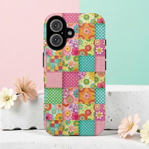 May include: A colorful phone case with a patchwork design. The case features squares of pink, green, and turquoise with floral and polka dot patterns. The phone's camera lenses are visible at the top.