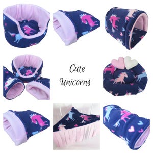 May include: A collection of small pet beds and tunnels made of dark blue fleece fabric with a pink and light blue unicorn and heart pattern, featuring light pink interior lining and two plush heart-shaped pillows. The text reads Cute Unicorns.