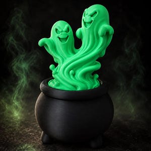 May include: A matte black three-legged cauldron with a bright green sculpted element emerging from the top. The green portion features two distinct ghost figures with expressive faces, connected by swirling, fluid-like shapes and textures.