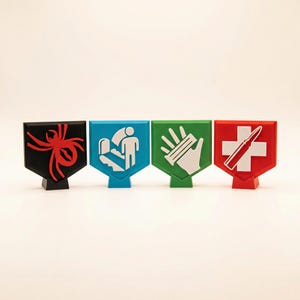 May include: Four colorful, shield-shaped game tokens. The tokens are black with a red spider, blue with a white person and toilet, green with a white hand and bullets, and red with a white cross and bullet.