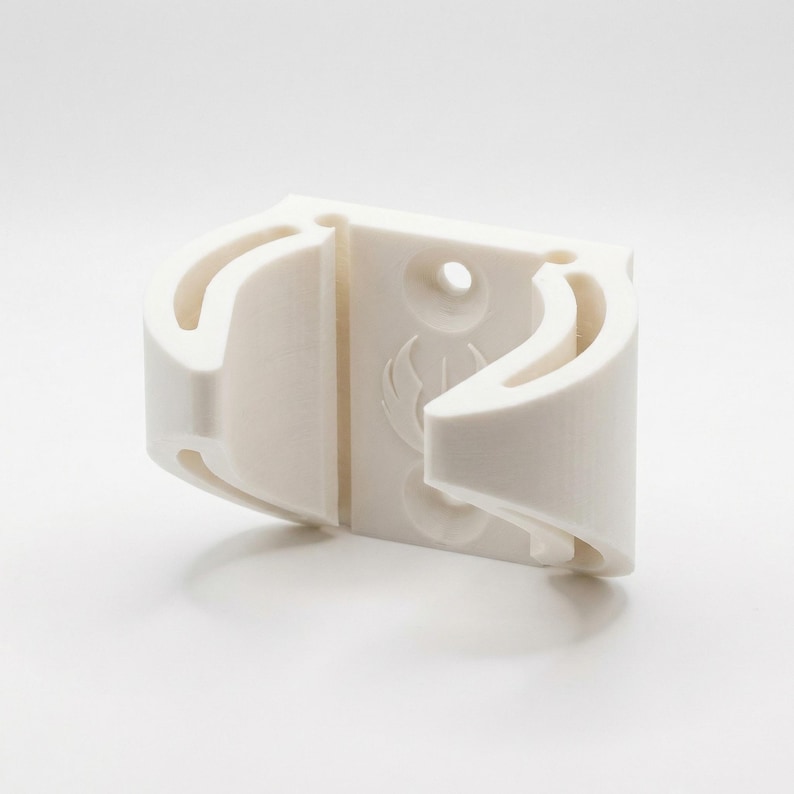 May include: A white, 3D-printed object with curved, open sections and a central, solid panel. The panel features a circular hole and a stylized emblem. The object appears to be a holder or mount, possibly for a specific item.