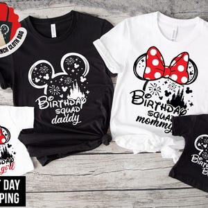May include: A collection of four t-shirts featuring graphic prints of Mickey and Minnie Mouse ears with fireworks and castle silhouettes. The shirts include text reading Birthday Squad daddy, Birthday Squad mommy, Birthday girl, and Birthday boy.