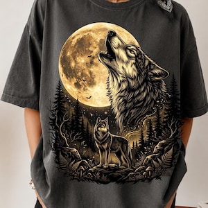 May include: A charcoal gray short-sleeve t-shirt featuring a graphic print of a wolf howling at a large yellow moon above a forest scene. A second wolf stands in the foreground among trees and ferns, with small bats flying near the moon.