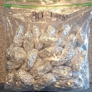 May include: A clear plastic resealable storage bag filled with numerous individual items wrapped in shiny silver aluminum foil. The bag features a green plastic zipper seal at the top and has the text 30 Large written in black marker on the front.
