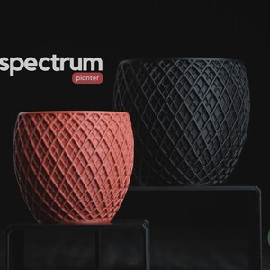 Peut inclure: Deux pots de fleurs ronds avec un motif en treillis texturé. L'un est de couleur terre cuite et l'autre est noir. Le texte "spectrum planter" apparaît en haut à gauche, et un logo circulaire "h3liø design" est en bas à droite.