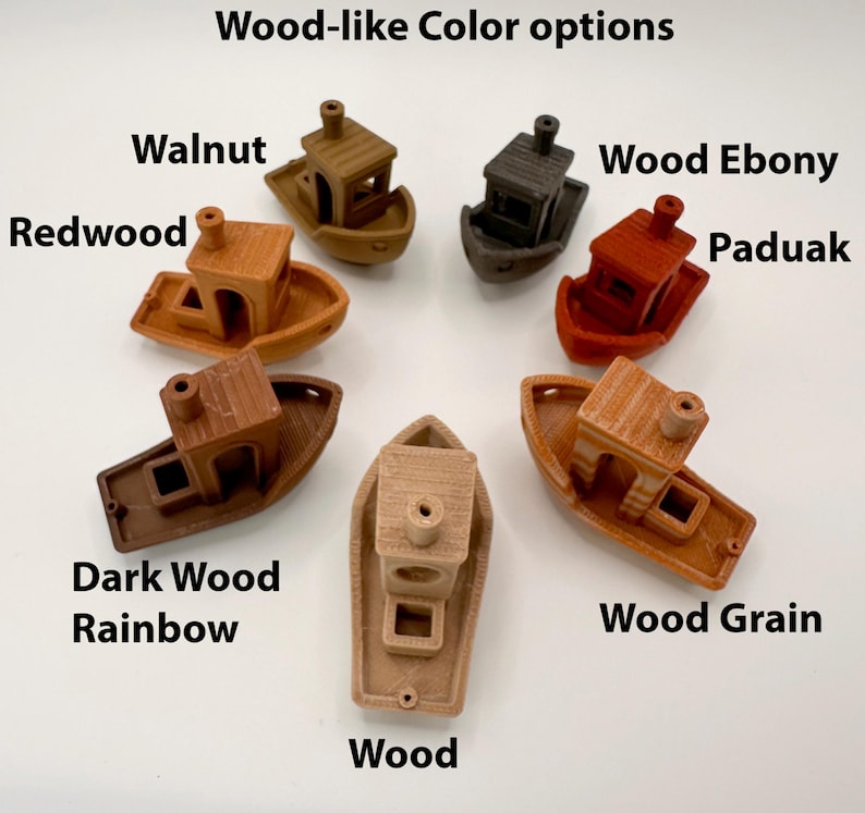 Pu&ograve; includere: Una collezione di piccoli oggetti decorativi a forma di barca in vari colori effetto legno. Le opzioni di colore includono Noce, Redwood, Ebano, Paduak, Dark Wood Rainbow, Legno e Venatura del legno. Il testo "Wood-like Color options" &egrave; in alto.
