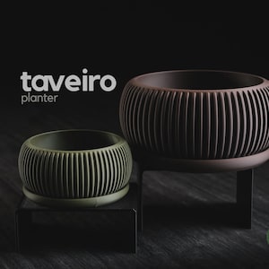 Könnte beinhalten: Zwei runde Pflanzgefäße mit vertikaler Rippenstruktur, eines olivgrün und eines dunkelbraun, die jeweils auf einem schwarzen Metallständer stehen. Der Text "taveiro planter" ist in Weiß und ein kleines grünes Logo "h3liø design" zu sehen.
