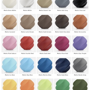 Pu&ograve; includere: Una griglia di oggetti decorativi a forma di spirale con finitura opaca in vari colori, tra cui bianco, grigio, marrone, rosa, rosso, blu, giallo e verde. Ogni oggetto &egrave; etichettato con il suo nome di colore, come "Matte Bone White" e "Matte Dark Green."