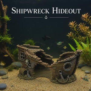 May include: A brown, weathered shipwreck aquarium ornament featuring a skull and crossbones emblem, a circular porthole, and a decorative anchor. The text SHIPWRECK HIDEOUT is displayed above the ornament, which sits on a sandy substrate.
