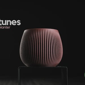 Peut inclure: Un pot de fleurs arrondi de couleur rouge foncé avec une texture nervurée verticale. Le texte 'tunes planter' apparaît dans le coin supérieur gauche et un logo vert circulaire avec le texte 'h3liø design' est situé en bas à droite.