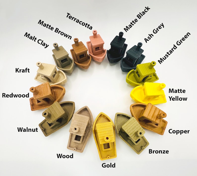Pu&ograve; includere: Una collezione di modelli di barche in miniatura in vari colori, tra cui Terracotta, Nero Opaco e Oro. Ogni barca presenta una cabina e un fumaiolo. L'immagine include etichette di testo per ogni colore, come "Verde Senape" e "Giallo Opaco."