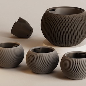 Könnte beinhalten: Eine Sammlung grauer und dunkelbrauner kugelförmiger Objekte mit strukturierten Oberflächen. Die Objekte umfassen eine große Kugel auf einer weißen Plattform, drei kleinere Kugeln und eine abgetrennte Komponente. Die Kugeln haben unterschiedliche Oberflächenmuster, darunter ein Rautenmuster und gebogene Linien.