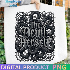 May include: White tote bag featuring a detailed black and gray illustration. The design includes two dragon-like creatures flanking the text "The Devil Herself." The artwork is surrounded by a thorny border. The words "DIGITAL PRODUCT PNG" are at the bottom.