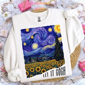 May include: White sweatshirt featuring a print of Van Gogh's "Starry Night" with sunflowers and the text "LET IT GOGH" in black. The artwork depicts a swirling night sky, a field of sunflowers, and a village.