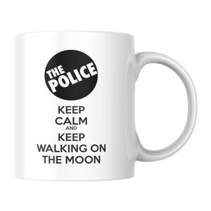 May include: White ceramic mug with the band name "The Police" in a black circle, and the text "Keep Calm and Keep Walking on the Moon" in black. The mug has a curved handle.