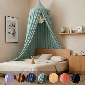 May include: A sage green fabric bed canopy hangs from the ceiling, draping over a wooden bed frame with beige bedding. A small wooden rabbit toy sits on the bed. Below the main image, eight circular swatches show the canopy in various colors.