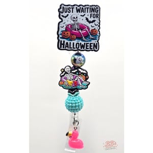 Peut inclure: Un enrouleur de badge avec un embout rectangulaire représentant un squelette dans une bouée rose et le texte JUST WAITING FOR HALLOWEEN, une perle irisée, un petit charm squelette, une perle turquoise texturée et un charm flamant rose.