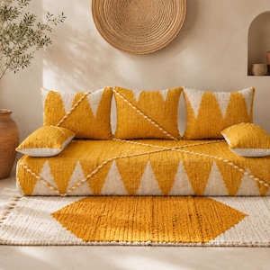 May include: A low-profile daybed featuring a textured mustard yellow and cream geometric zigzag pattern, accompanied by three square cushions and two rectangular bolsters, all matching the same yellow and cream color scheme and design.