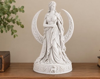 May include: A white statue of a standing figure holding a bow, positioned in front of a crescent moon backdrop. The circular base features a small deer relief and leaf motifs. The figure wears a draped garment with a brooch at the chest.