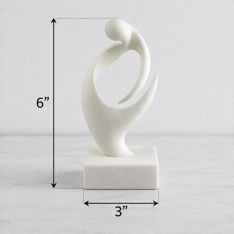 May include: A white abstract sculpture featuring a smooth, curved form mounted on a square base. The sculpture measures 6 inches in height and 3 inches in width, as indicated by the black dimension lines and arrows visible in the image.