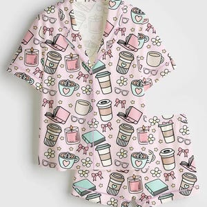 May include: A light pink pajama set featuring a repeating pattern of coffee cups, books, candles, eyeglasses, bows, and flowers. The short-sleeved top and shorts are made of a soft material.