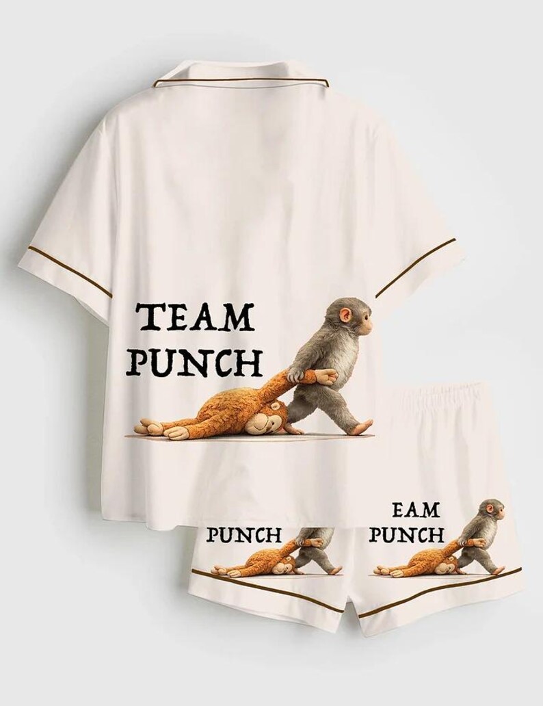 Puede incluir: Conjunto de pijama blanco con ribete marr&oacute;n, con el texto "TEAM PUNCH" en la camisa y "PUNCH" en los pantalones cortos. El dise&ntilde;o incluye un mono de dibujos animados tirando de otro mono. Un conjunto de ropa de dormir divertido y juguet&oacute;n.