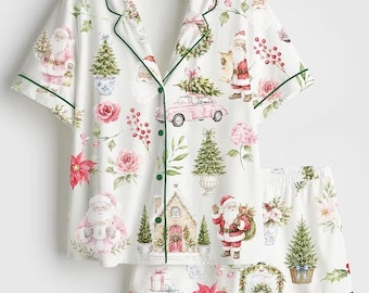 May include: A white short-sleeve button-down pajama shirt and matching shorts set featuring a festive print of Santa Claus, pink vintage cars, Christmas trees, poinsettias, and wreaths with dark green piping along the collar and edges.