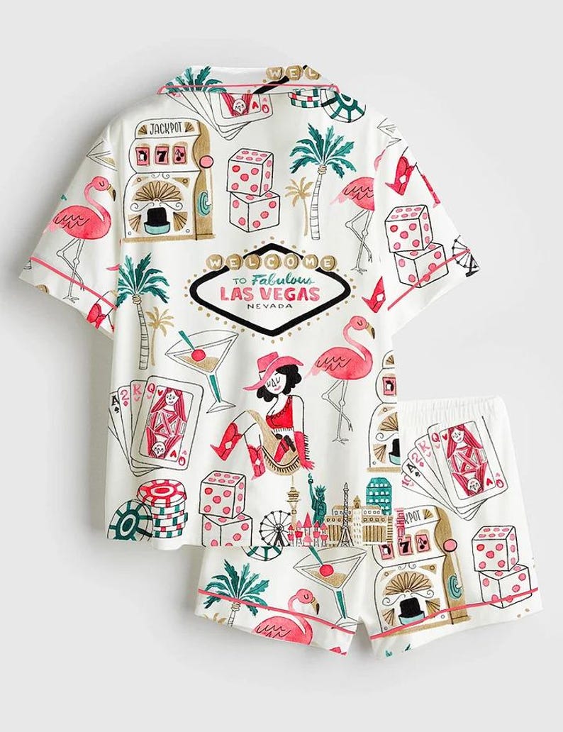 May include: White short-sleeved shirt and shorts set with a Las Vegas theme. The set features illustrations of slot machines, dice, playing cards, flamingos, and the text "Welcome to Fabulous Las Vegas Nevada."