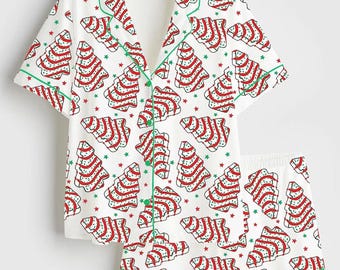 May include: A white short-sleeve pajama set featuring a repeating pattern of red and white striped Christmas tree cookies with green sprinkles and small green stars. The button-down shirt has a notched collar and green piping trim.