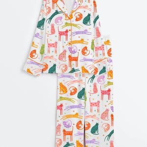 Może przedstawiać: Biały ceramiczny kubek z czarnym uchwytem i napisem "But First, Coffee" w stylu odręcznym. Kubek stoi na białej powierzchni. Kubek ma około 10 cm wysokości.