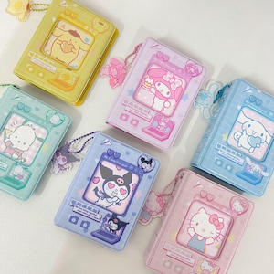 Peut inclure: Plusieurs petits albums photo carrés aux couleurs pastel. Chaque album présente un personnage de dessin animé différent, comme Hello Kitty et My Melody, avec des breloques assorties. Les albums sont de couleurs jaune, rose, bleu et vert.