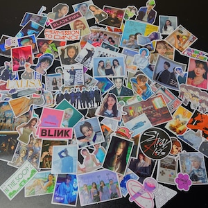 May include: A collection of colorful stickers featuring various K-pop artists and groups. The stickers include images of performers, album art, and text such as "BLACKPINK", "PERMISSION TO DANCE", and "LALISA". The stickers are scattered on a dark surface.